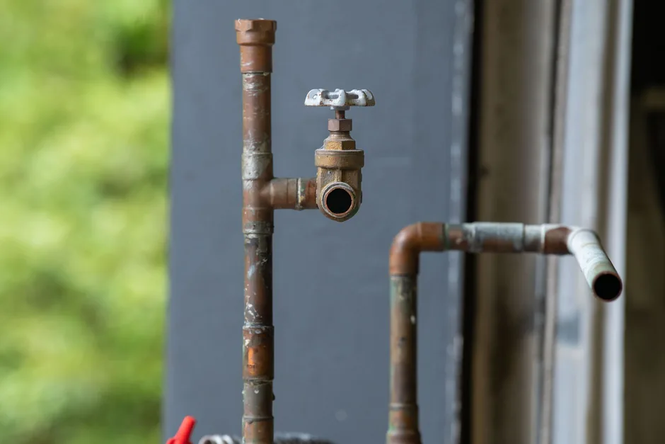 An ageing brass gate valve on corroded copper pipework